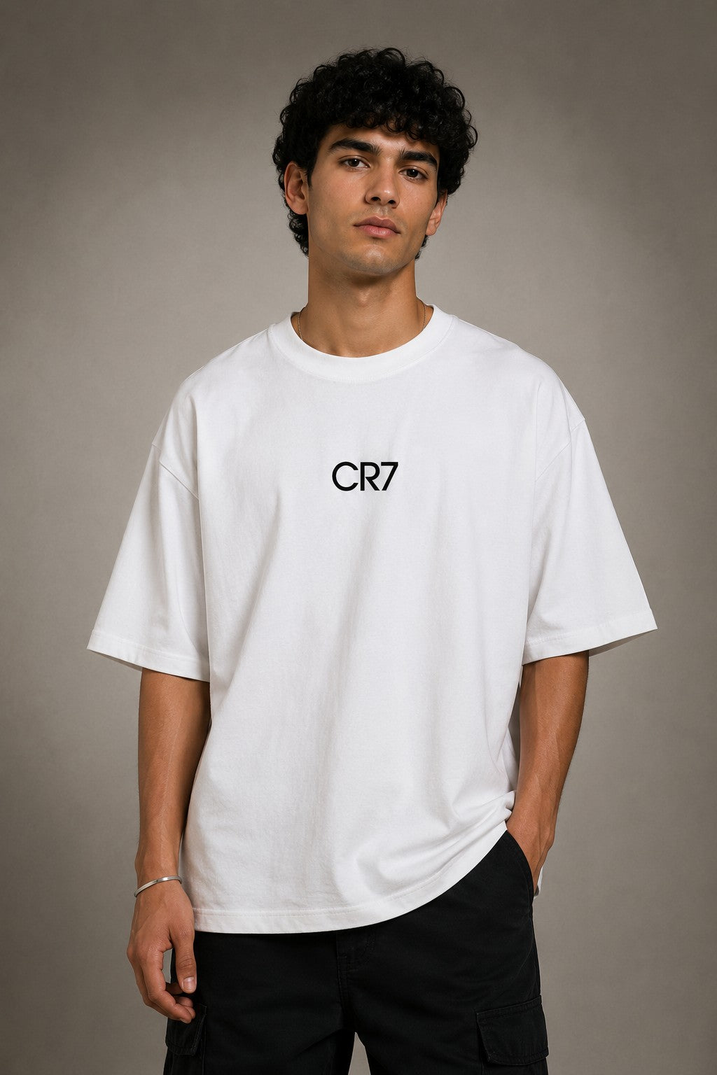 Man wearing a white CR7 oversized t-shirt with black CR7 logo. Studio shot with grey background.