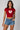 Model wearing a red CROPTOP Cherry crop top with a cute cherry and bow graphic, paired with denim shorts. The top has a flattering cropped fit. - red