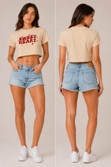 Model wearing a white "Sweet Heart" graphic oversized croptop t-shirt with red distressed lettering and star accents. Streetwear fashion.