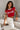 Back view of a woman wearing a red Coco-Cola crop top with white trim and beige high-waisted pants against a white background.