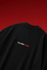On a Diet Coke black oversized t-shirt with white and red chest print