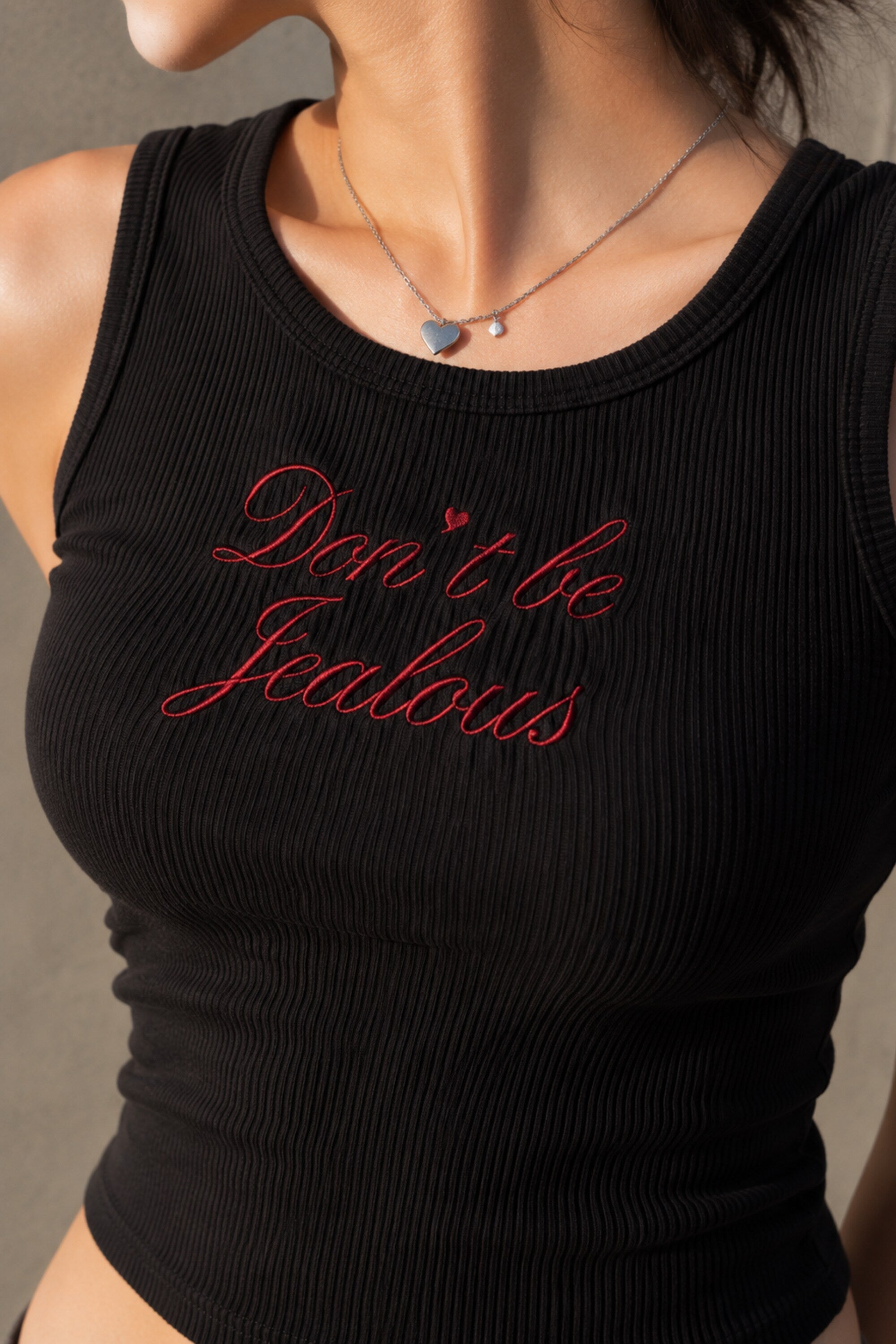 Black ribbed crop tank top with red cursive Don't Be Jealous embroidery on model