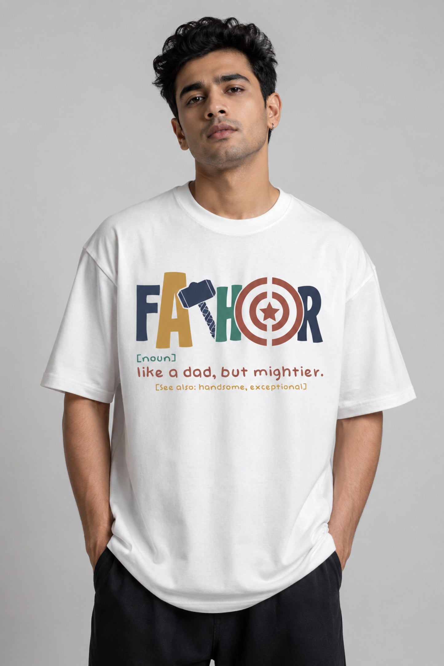 Man wearing a white oversized FAKR t-shirt with a graphic design of the word "Fakr" integrated with superhero symbols, on a plain gray background.