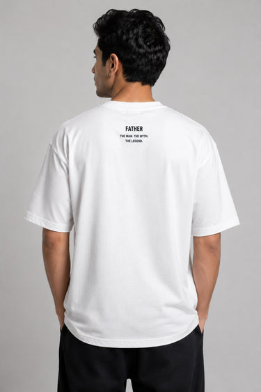 Man wearing a white oversized FAKR t-shirt with a graphic design of the word "Fakr" integrated with superhero symbols, on a plain gray background.