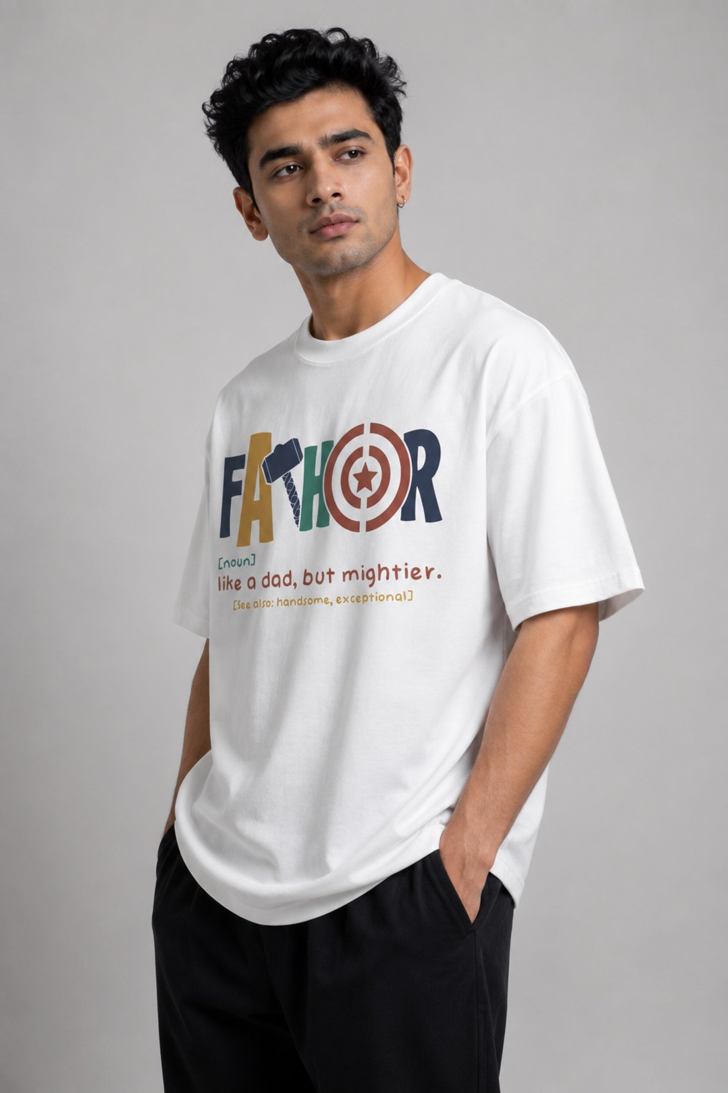 Man wearing a white oversized FAKR t-shirt with a graphic design of the word "Fakr" integrated with superhero symbols, on a plain gray background.
