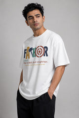 Man wearing a white oversized FAKR t-shirt with a graphic design of the word "Fakr" integrated with superhero symbols, on a plain gray background.