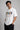 Man wearing a white oversized FAKR t-shirt with a graphic design of the word "Fakr" integrated with superhero symbols, on a plain gray background.