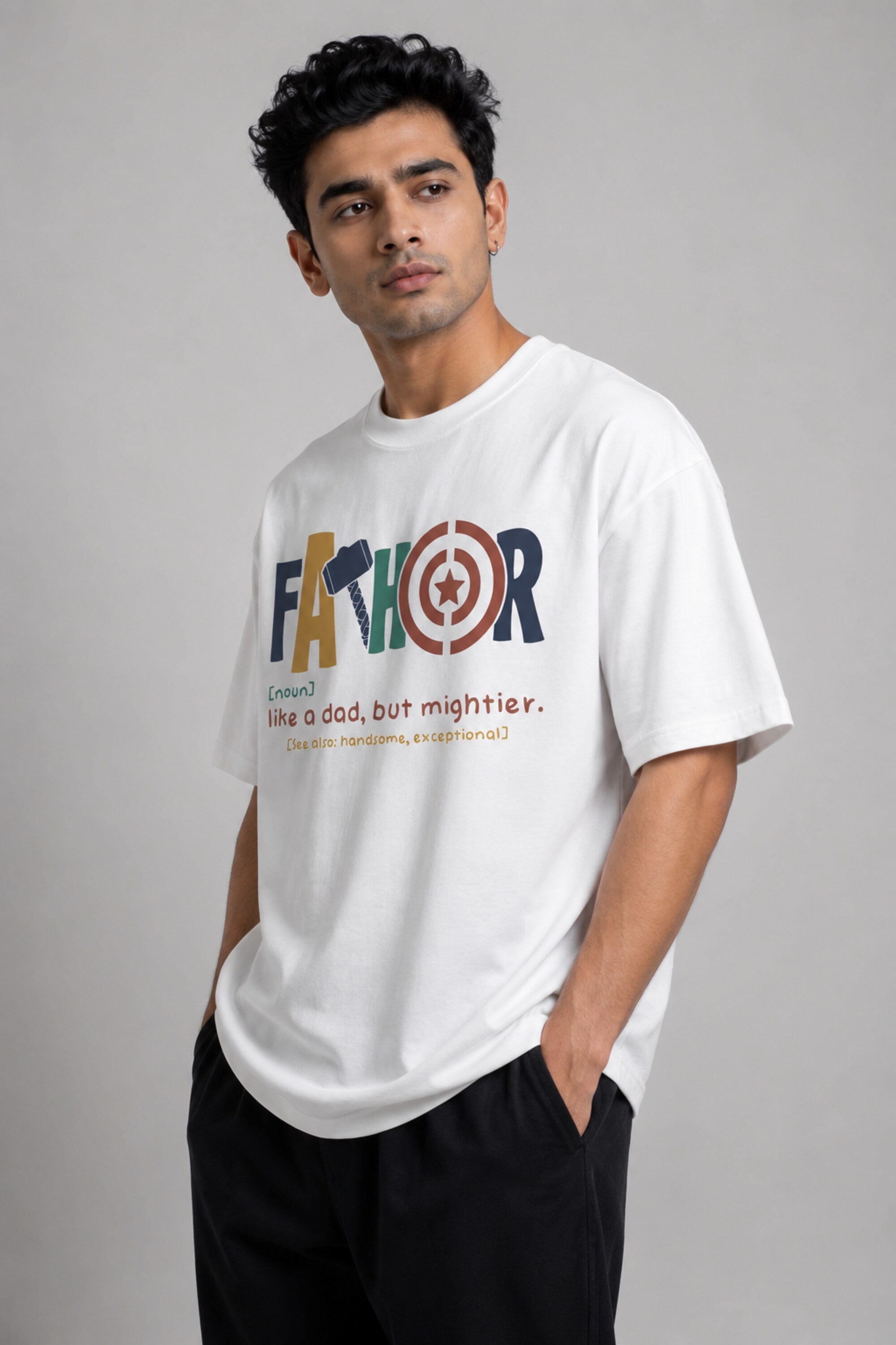 Man wearing a white oversized FAKR t-shirt with a graphic design of the word "Fakr" integrated with superhero symbols, on a plain gray background.