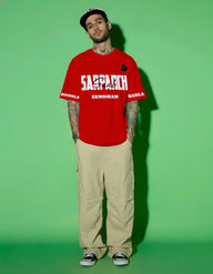Person wearing a Punjab red t-shirt with text on a green background