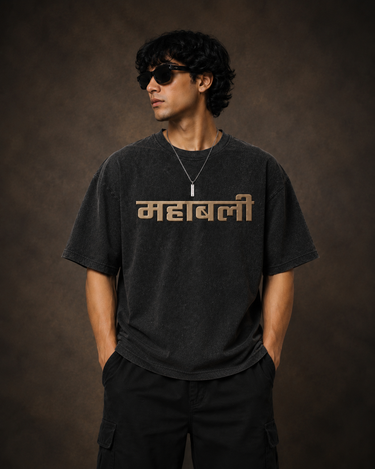 Man wearing an anthracite black 85-DENIM oversized t-shirt featuring a vibrant Hanumanji graphic print and Hindi text 'Mahabali' on the back. Styled for streetwear.
