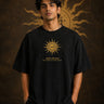 Model wearing a black KARMA oversized t-shirt with a golden sun graphic and the Sanskrit phrase 'कर्मण्येवाधिकारस्ते' (Your right is to action alone). - black