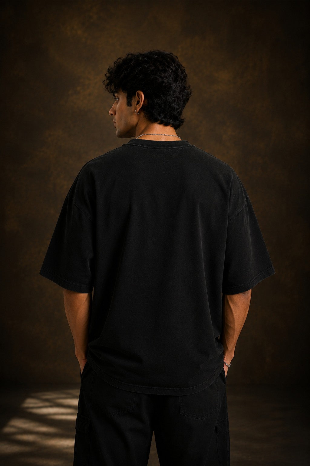 Model wearing a black KARMA oversized t-shirt with a golden sun graphic and the Sanskrit phrase 'कर्मण्येवाधिकारस्ते' (Your right is to action alone).
