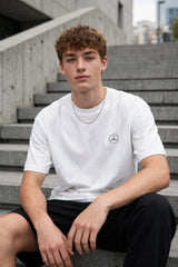Model wearing white POPCASE Kimi Antonelli Mercedes oversized t shirt with teal MERCEDES Petronas F1 car back graphic and bio text