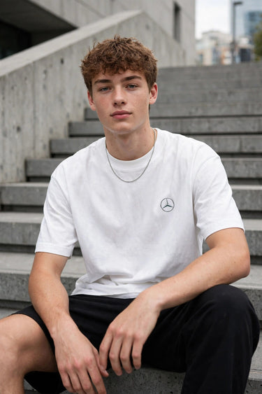 Model wearing white POPCASE Kimi Antonelli Mercedes oversized t shirt with teal MERCEDES Petronas F1 car back graphic and bio text