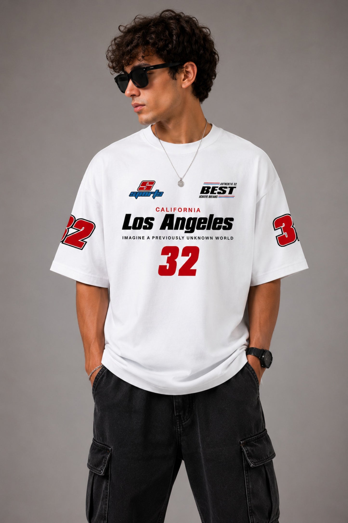 Back view of a man wearing a white LA 32 Drive oversized t-shirt with black text graphic. Model wears black cargo pants. - white