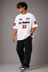 Back view of a man wearing a white LA 32 Drive oversized t-shirt with black text graphic. Model wears black cargo pants.