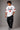 Back view of a man wearing a white LA 32 Drive oversized t-shirt with black text graphic. Model wears black cargo pants.