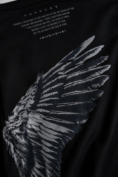 Black POPCASE LAUNCH oversized t-shirt featuring a large, distressed gray wing graphic print. Close-up on the premium fabric and detailed print for a streetwear aesthetic.