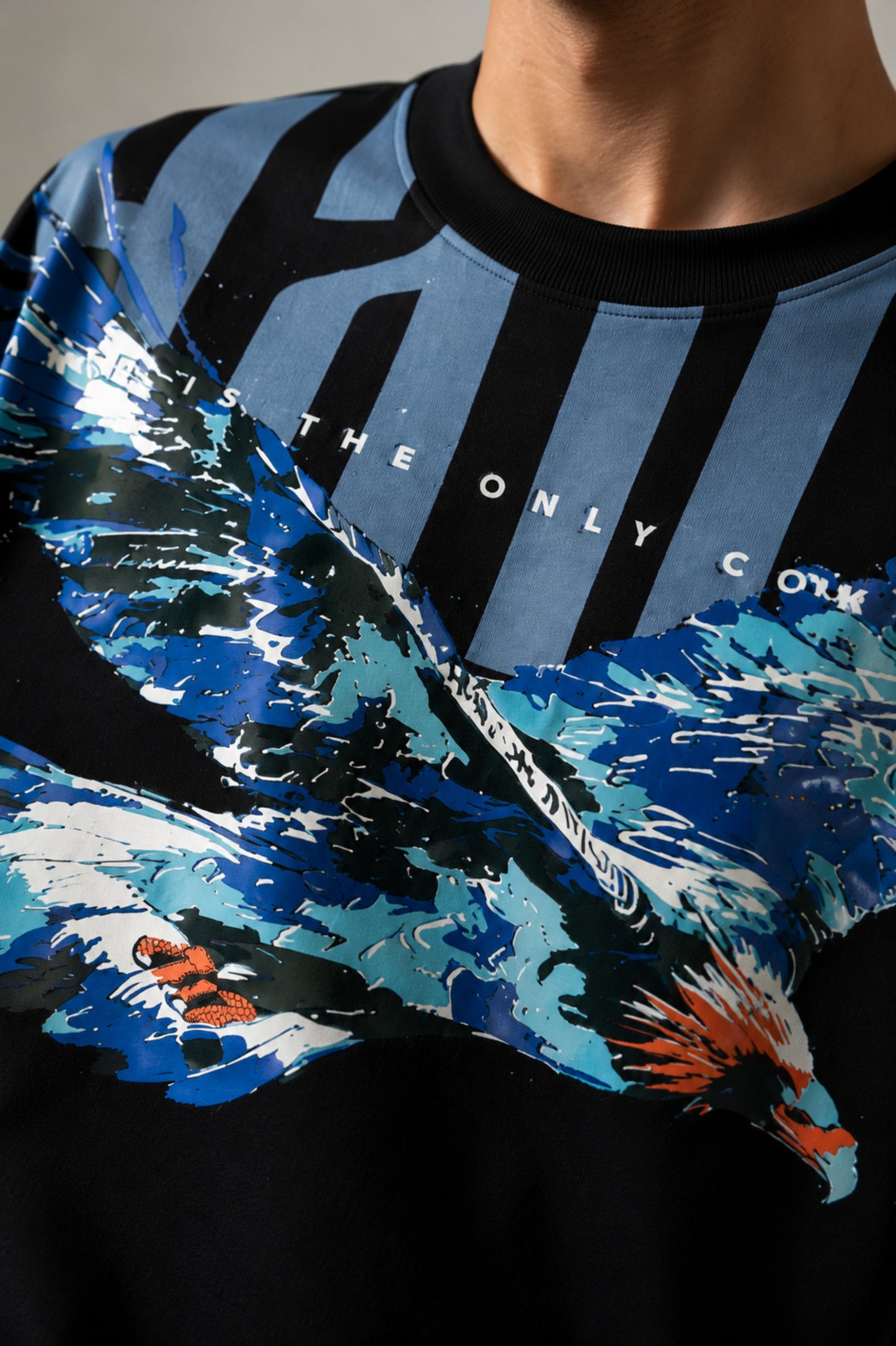 LAYERS black oversized t-shirt with a dynamic blue, white, and orange abstract graphic print, featuring "THE ONLY C" text detail, showcasing its premium fabric and streetwear aesthetic.