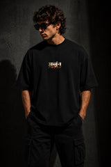 Black MIGHTY ARJUN oversized t-shirt featuring distressed Hindi script graphic in beige and orange, highlighting streetwear style. - black