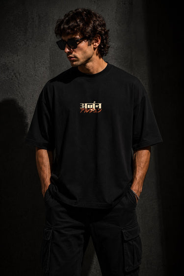Black MIGHTY ARJUN oversized t-shirt featuring distressed Hindi script graphic in beige and orange, highlighting streetwear style. - black