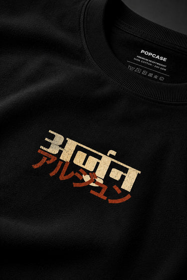 Black MIGHTY ARJUN oversized t-shirt featuring distressed Hindi script graphic in beige and orange, highlighting streetwear style.