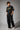 Model wearing an anthracite black Mbappe oversized t-shirt with gold "MBAPPE" graphic and signature, Real Madrid and number 7 logos on sleeves.