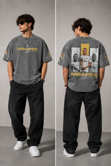 Model wearing an anthracite black Mbappe oversized t-shirt with gold "MBAPPE" graphic and signature, Real Madrid and number 7 logos on sleeves. - stone grey