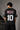 Man wearing an anthracite black Messi oversized t-shirt with a circular team logo and signature, showcasing the relaxed fit and premium fabric. - anthracite black