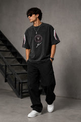 Man wearing an anthracite black Messi oversized t-shirt with a circular team logo and signature, showcasing the relaxed fit and premium fabric.