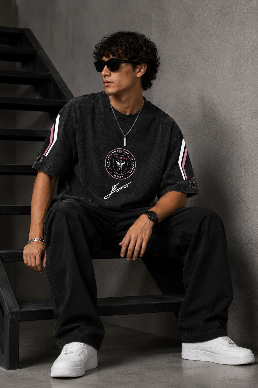 Man wearing an anthracite black Messi oversized t-shirt with a circular team logo and signature, showcasing the relaxed fit and premium fabric.