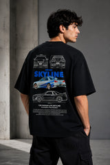 Black oversized t-shirt featuring a detailed white blueprint and a silver Nissan Skyline R34 with blue racing stripes graphic. Includes text 'The Nissan Skyline GTR'.