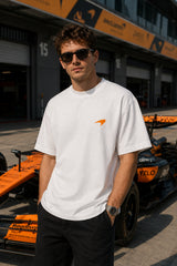 Model wearing white POPCASE Oscar Piastri McLaren oversized t shirt with orange McLaren speed mark logo and McLaren race car back graphic