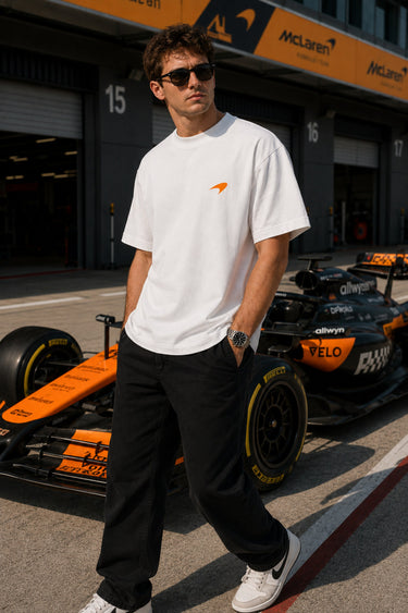 Model wearing white POPCASE Oscar Piastri McLaren oversized t shirt with orange McLaren speed mark logo and McLaren race car back graphic