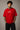 Model wearing a red oversized t-shirt with 'Just a 90's Kid' graphic. The tee has a relaxed fit, paired with black jeans and white sneakers, embodying a retro streetwear style. - red