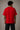 Model wearing a red oversized t-shirt with 'Just a 90's Kid' graphic. The tee has a relaxed fit, paired with black jeans and white sneakers, embodying a retro streetwear style.