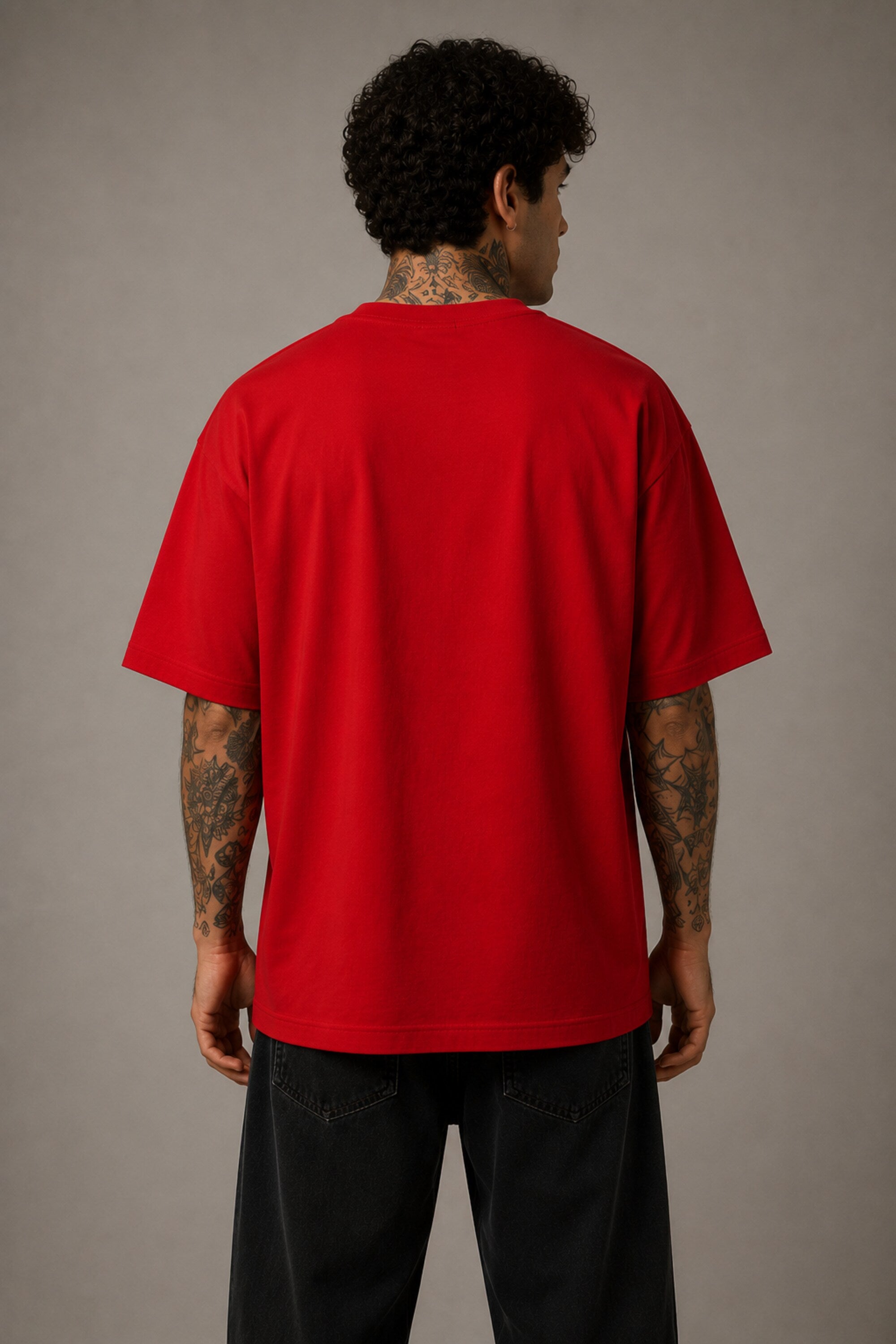 Model wearing a red oversized t-shirt with 'Just a 90's Kid' graphic. The tee has a relaxed fit, paired with black jeans and white sneakers, embodying a retro streetwear style.