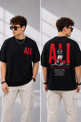 Man wearing a white ALI oversized t-shirt and beige cargo pants, sitting on grey stairs. He wears black sunglasses and jewelry. - black
