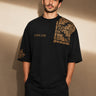 Back view of a person wearing a black ART ON OVERSIZED TSHIRT with gold embroidered detail on the left sleeve. Shows the oversized fit and premium streetwear aesthetic. - black