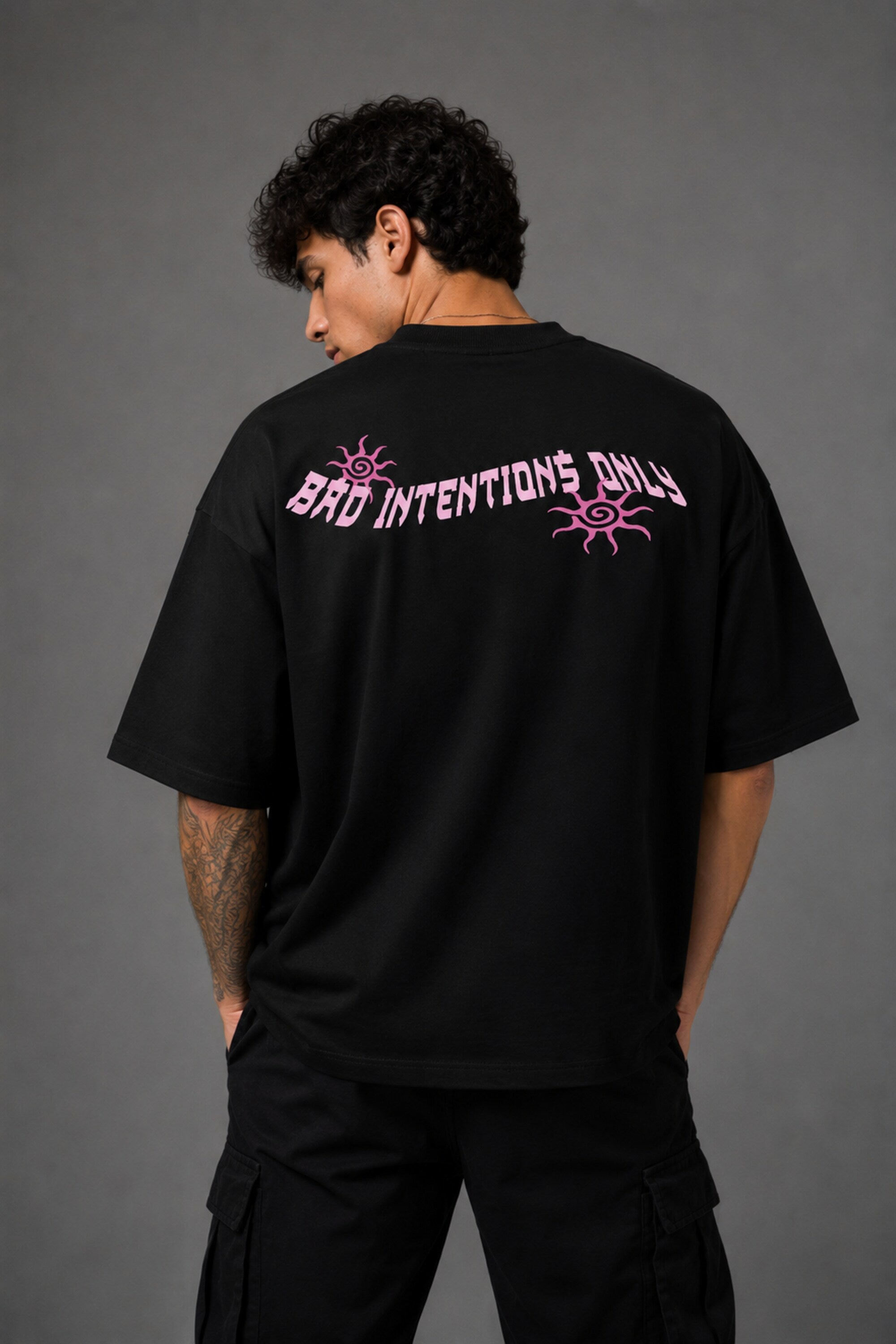 Black POPCASE oversized tshirt with Bad Intentions Only pink gothic text and tribal sun print on back, worn with black cargo pants