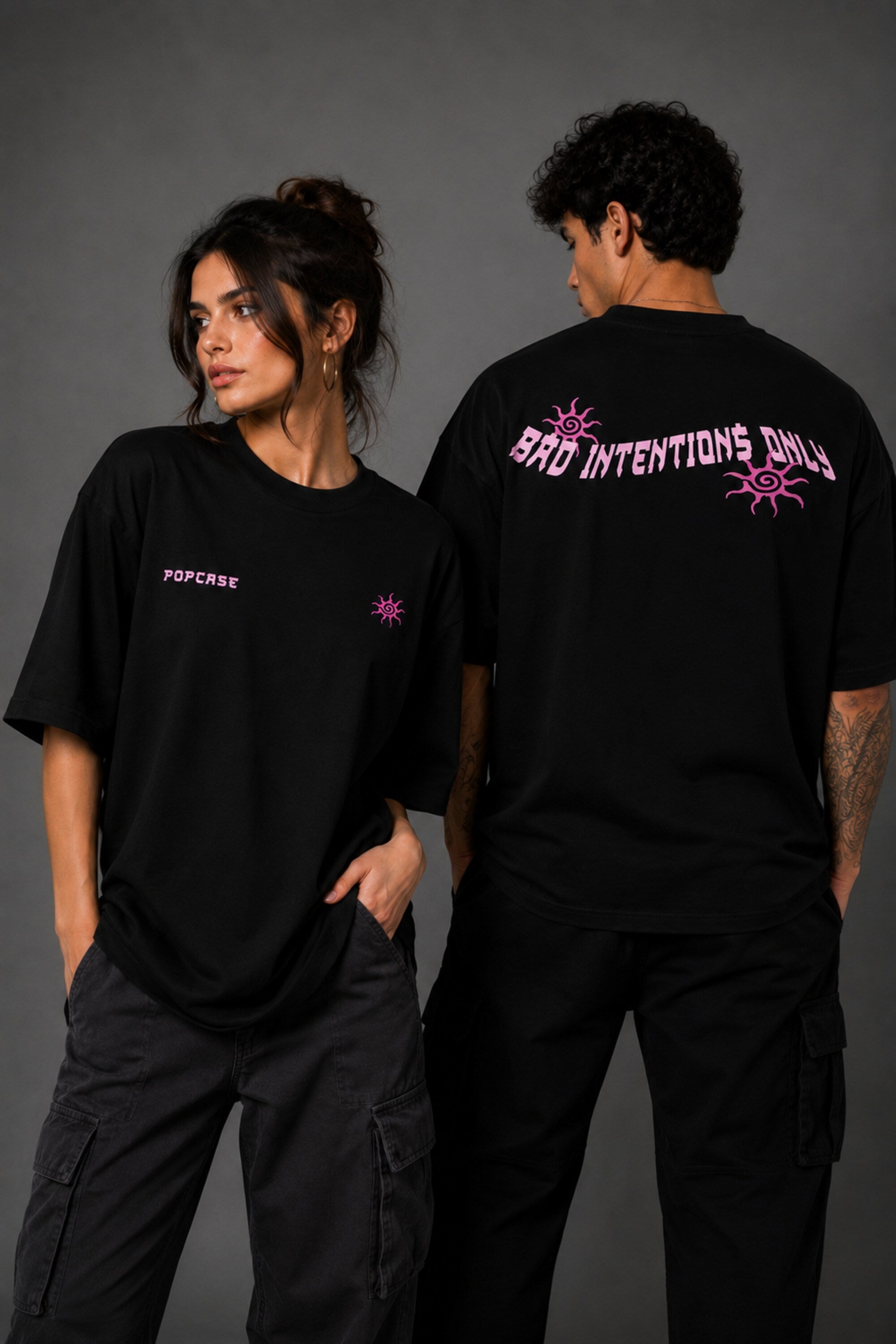 Black POPCASE oversized tshirt with Bad Intentions Only pink gothic text and tribal sun print on back, worn with black cargo pants