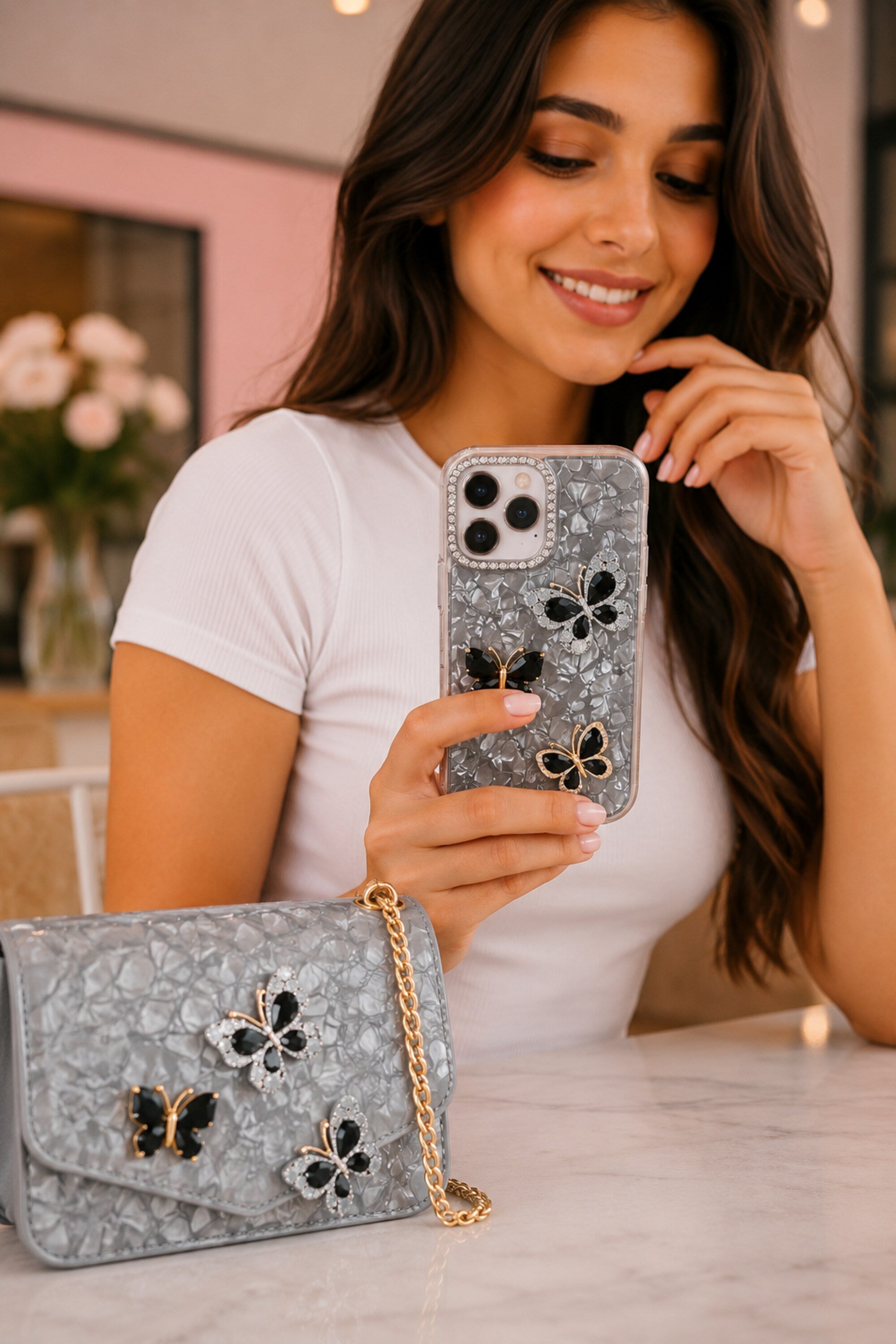 Woman holding a phone with a floral case and a matching handbag with butterfly designs.
