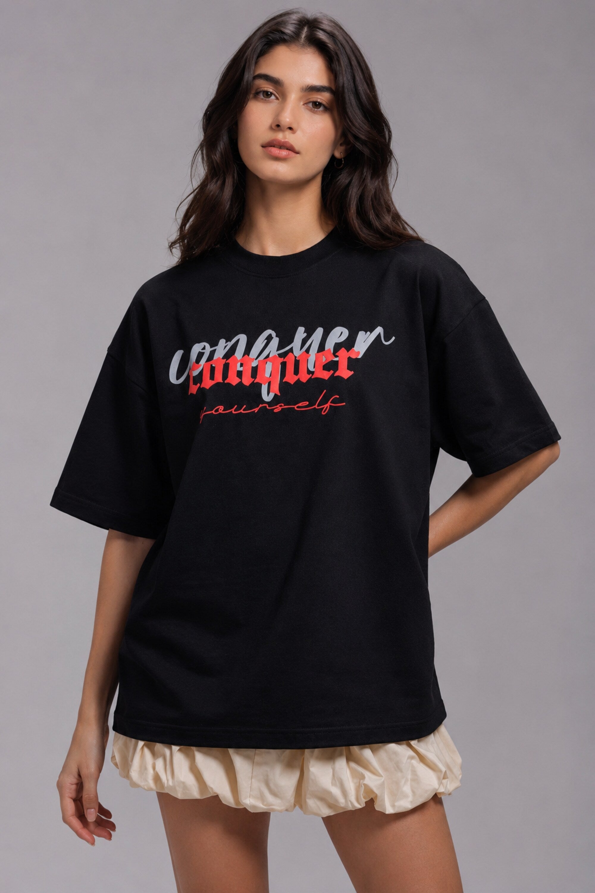 Black POPCASE oversized unisex tshirt with Conquer Yourself in layered red gothic and grey shadow text on front, styled with beige bubble shorts