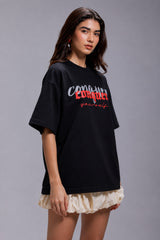 Black POPCASE oversized unisex tshirt with Conquer Yourself in layered red gothic and grey shadow text on front, styled with beige bubble shorts