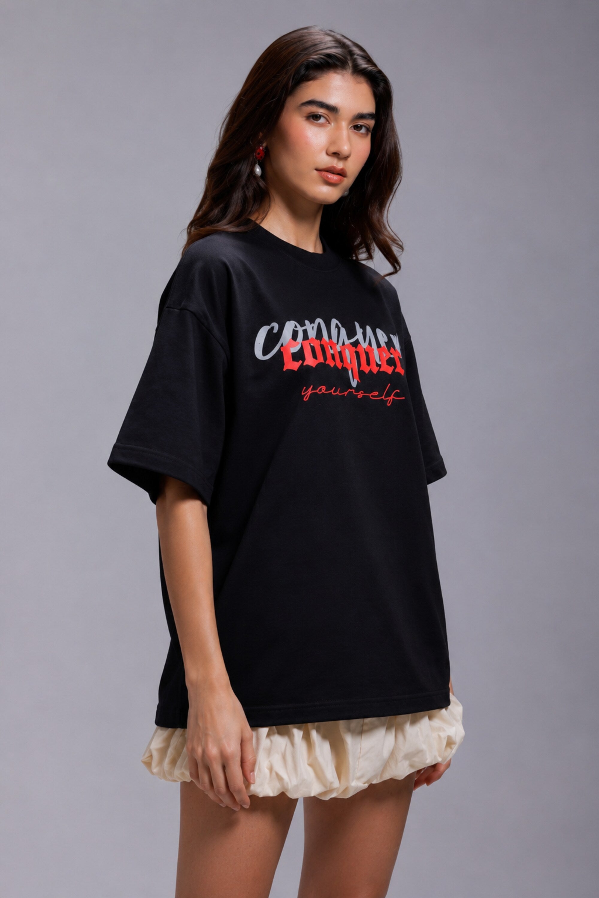 Black POPCASE oversized unisex tshirt with Conquer Yourself in layered red gothic and grey shadow text on front, styled with beige bubble shorts
