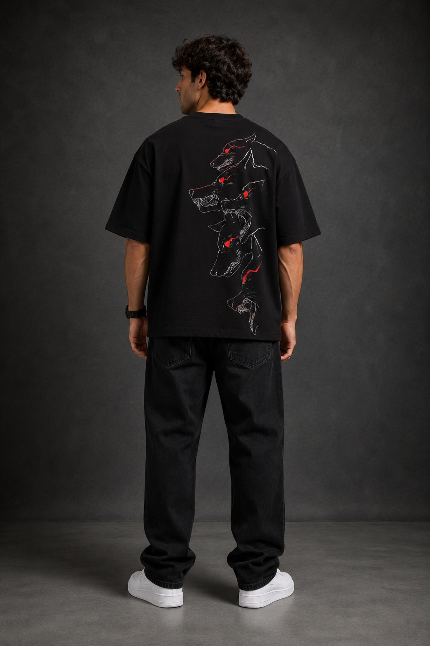Man wearing a black DISCIPLINE WILD WOLF oversized t-shirt with white 'DISCIPLINE' text, dark wash jeans, and white sneakers, sitting on stairs.