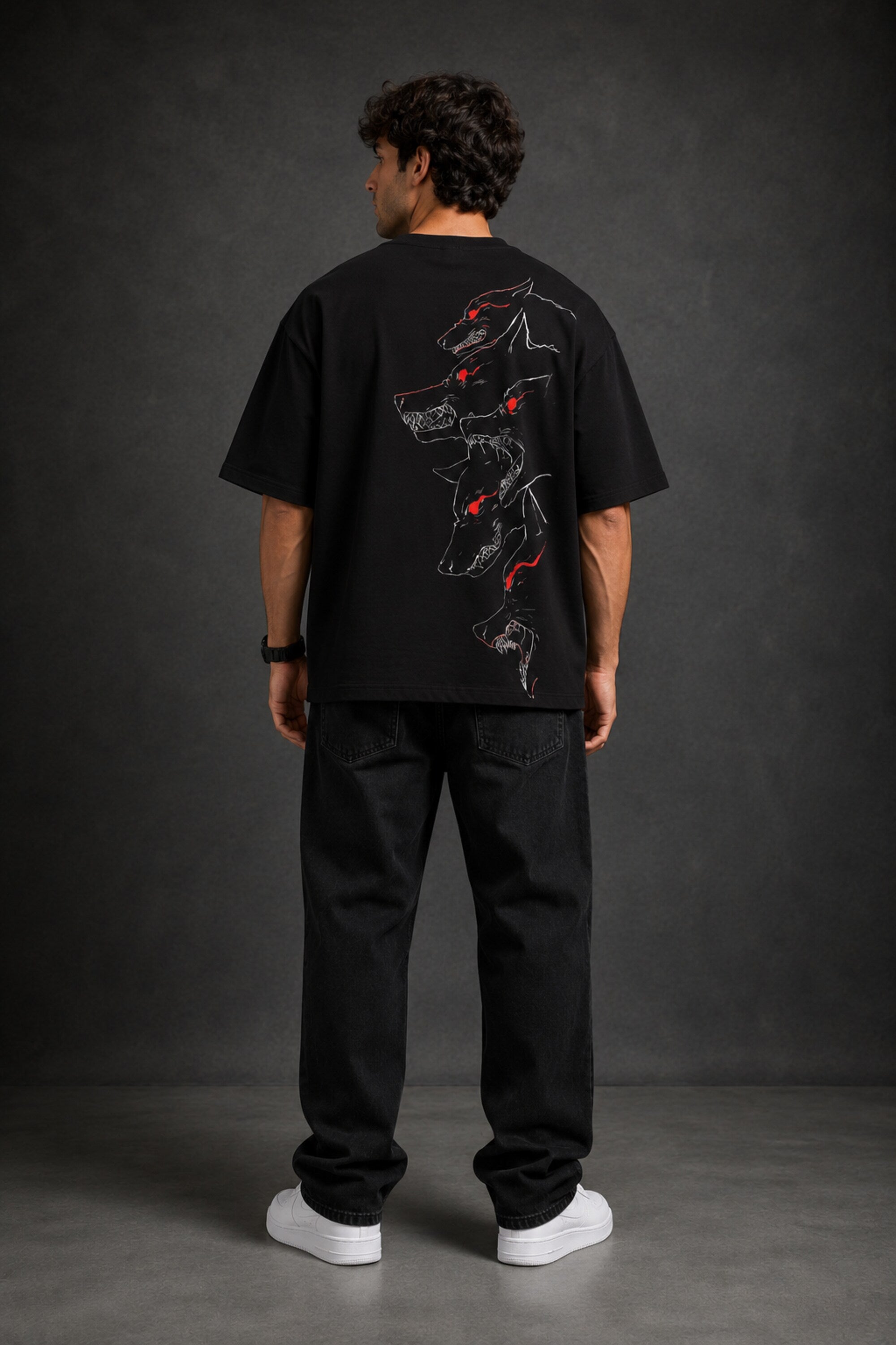 Man wearing a black DISCIPLINE WILD WOLF oversized t-shirt with white 'DISCIPLINE' text, dark wash jeans, and white sneakers, sitting on stairs.