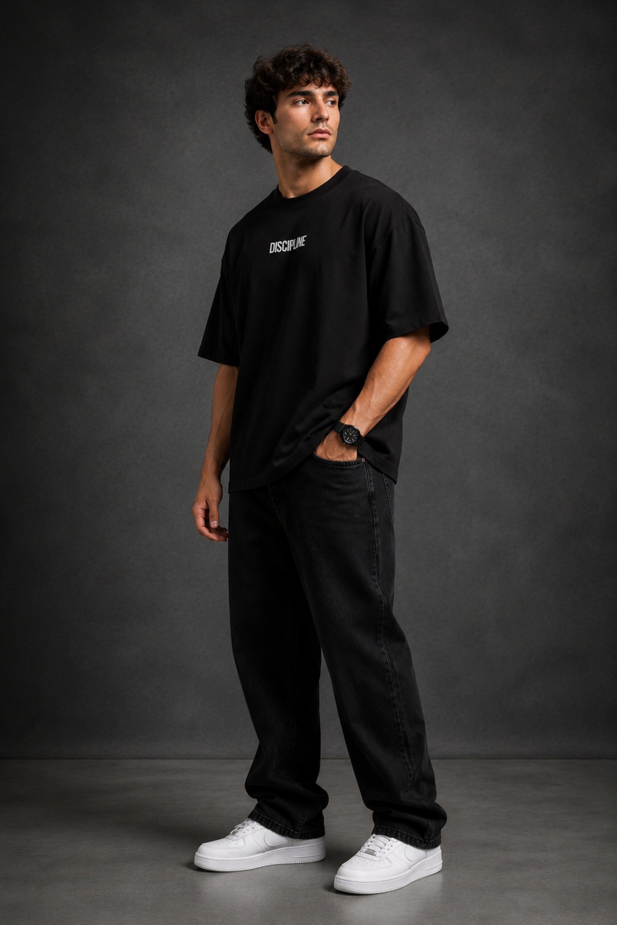 Man wearing a black DISCIPLINE WILD WOLF oversized t-shirt with white 'DISCIPLINE' text, dark wash jeans, and white sneakers, sitting on stairs.