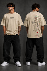Man wearing a black DISCIPLINE WILD WOLF oversized t-shirt with white 'DISCIPLINE' text, dark wash jeans, and white sneakers, sitting on stairs. - beige