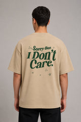Back view of a man wearing a beige RARE INSIGHT oversized t-shirt with a green "Sorry But I Don't Care" graphic and star accents.